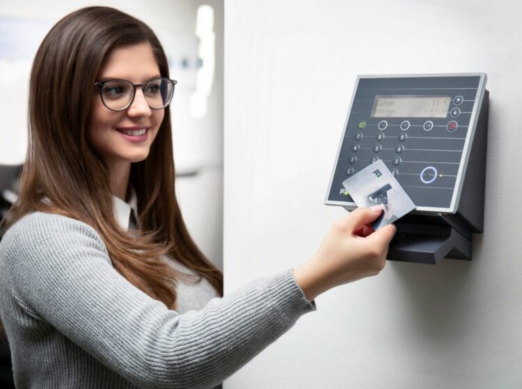 Smiling woman uses a card reader for secure office access in Munich.
