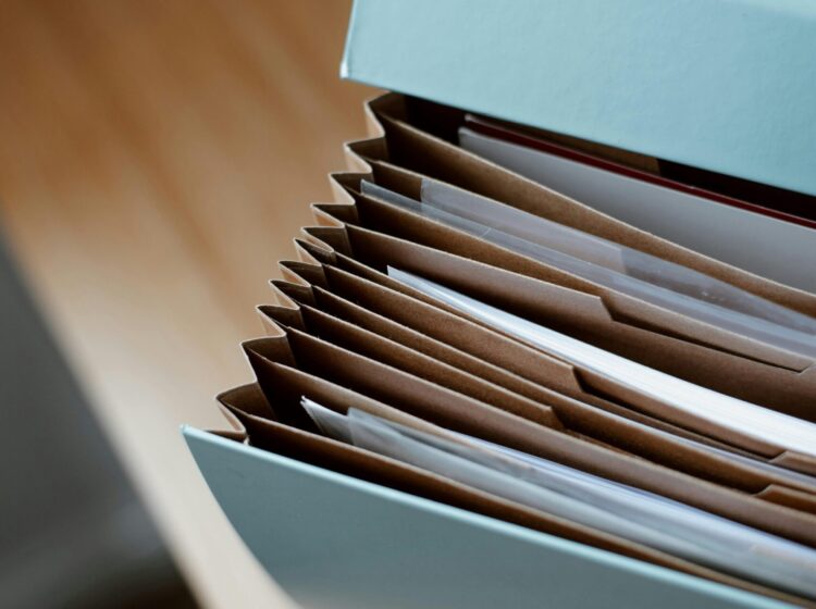 High angle of opened briefcase for documents with papers accosted in order placed on wooden table