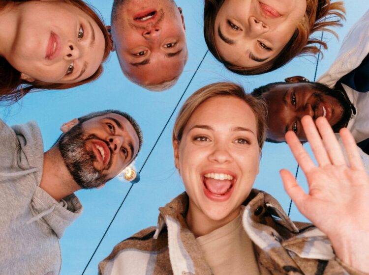 A diverse group of friends smiling into a camera outdoors, capturing a joyful moment.