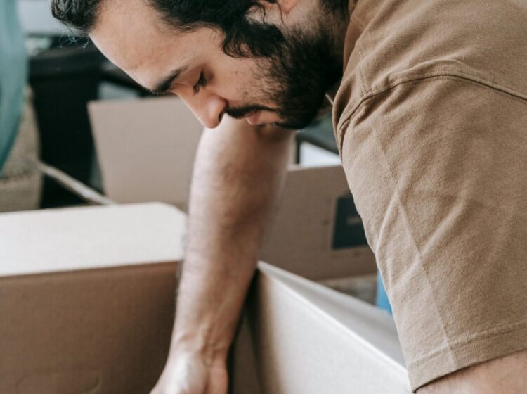 A man packs books into boxes while relocating, illustrating organization during moving.