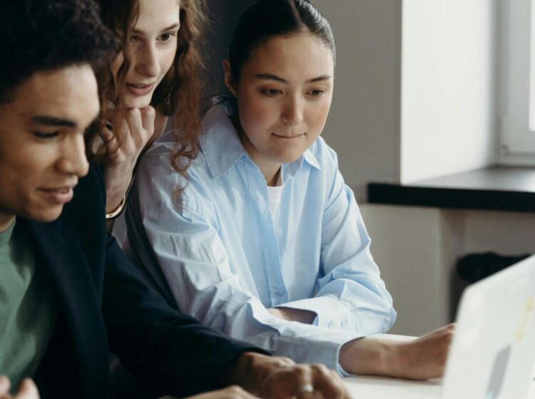 A diverse team of professionals collaborating on a laptop in an office setting.